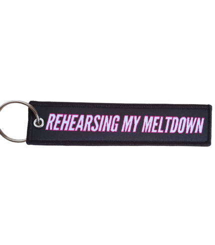 Rehearsing My Meltdown keychain in white text with pink bordering against a black background